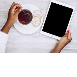 Woman looking at tablet while traveling and drinking coffee