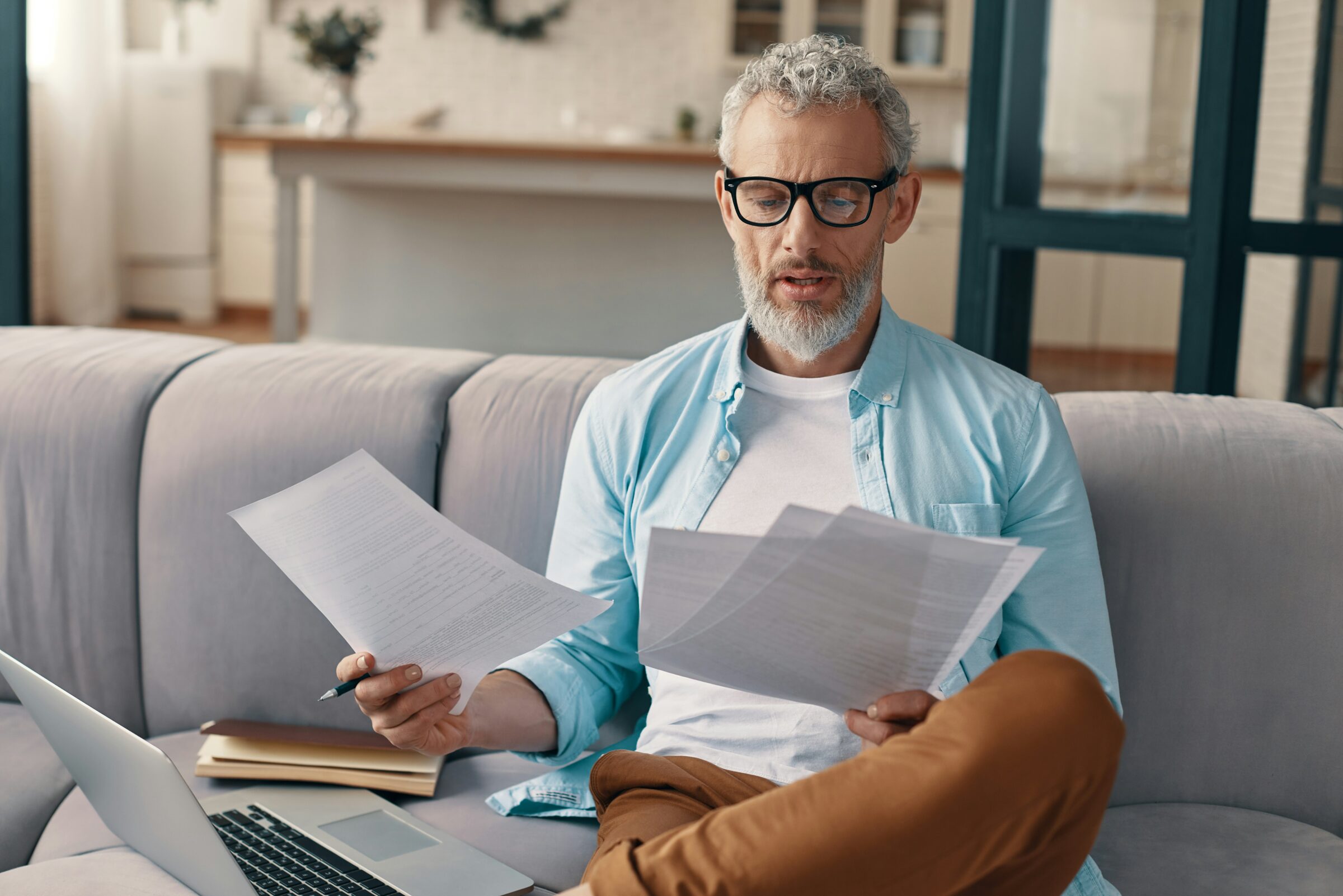 Man sitting on the couch reviewing travel insurance papers