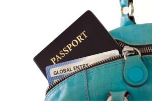 A turquoise purse with a passport and Global Entry card peeking out of the corner