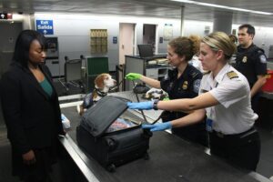 Woman having her luggage inspected by customs.