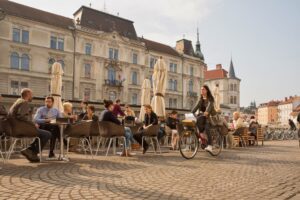 Woman riding a bike past a cafe in Ljubljana