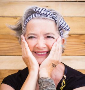 Smiling gray-haired woman wearing a travel bandana as a hairband.