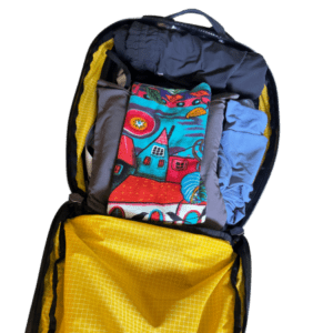 A backpack with a Trtl and clothes packed in the hollow space.