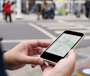 Man on the street holding a phone with a map displayed.